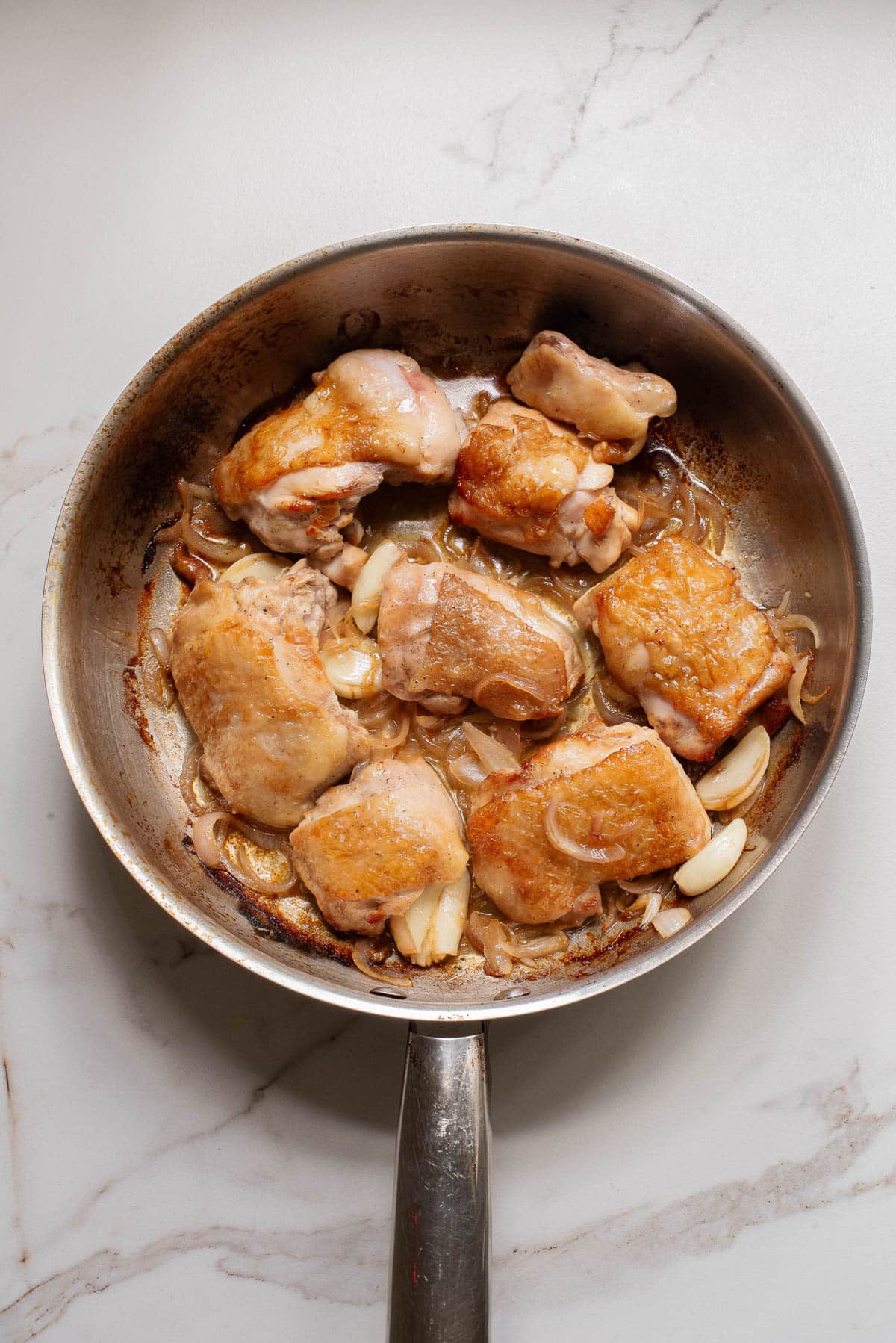 Cooked chicken thighs in a skillet.