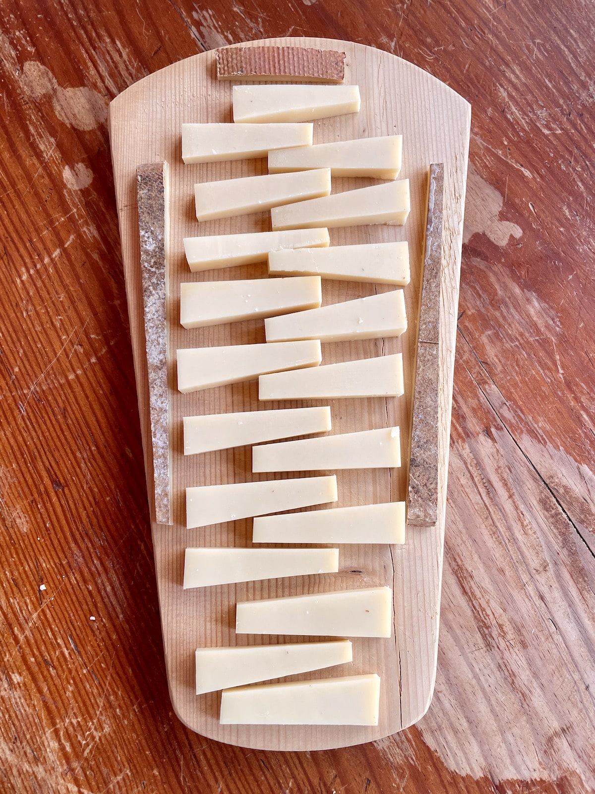 Young Comte cheese on a wood board on a wood table.