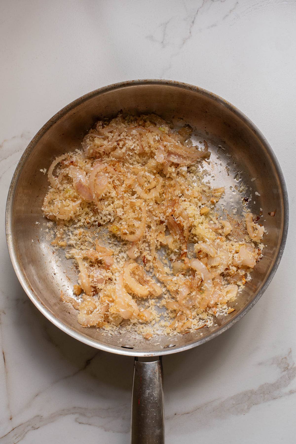 Cooked onions and Panko breadcrumbs in pan.