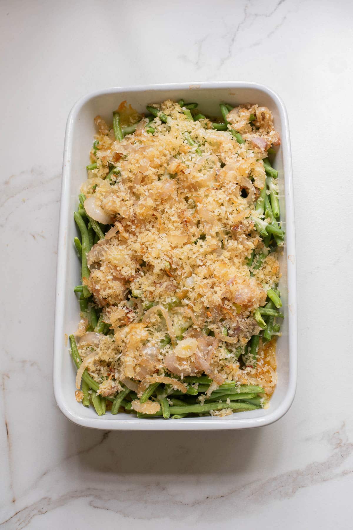 Green beans in white baking dish with crispy onion topping.