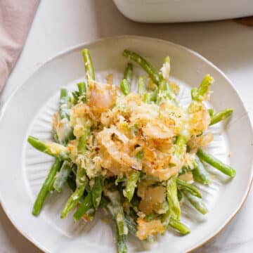 Green bean casserole with crispy onions on a white plate.