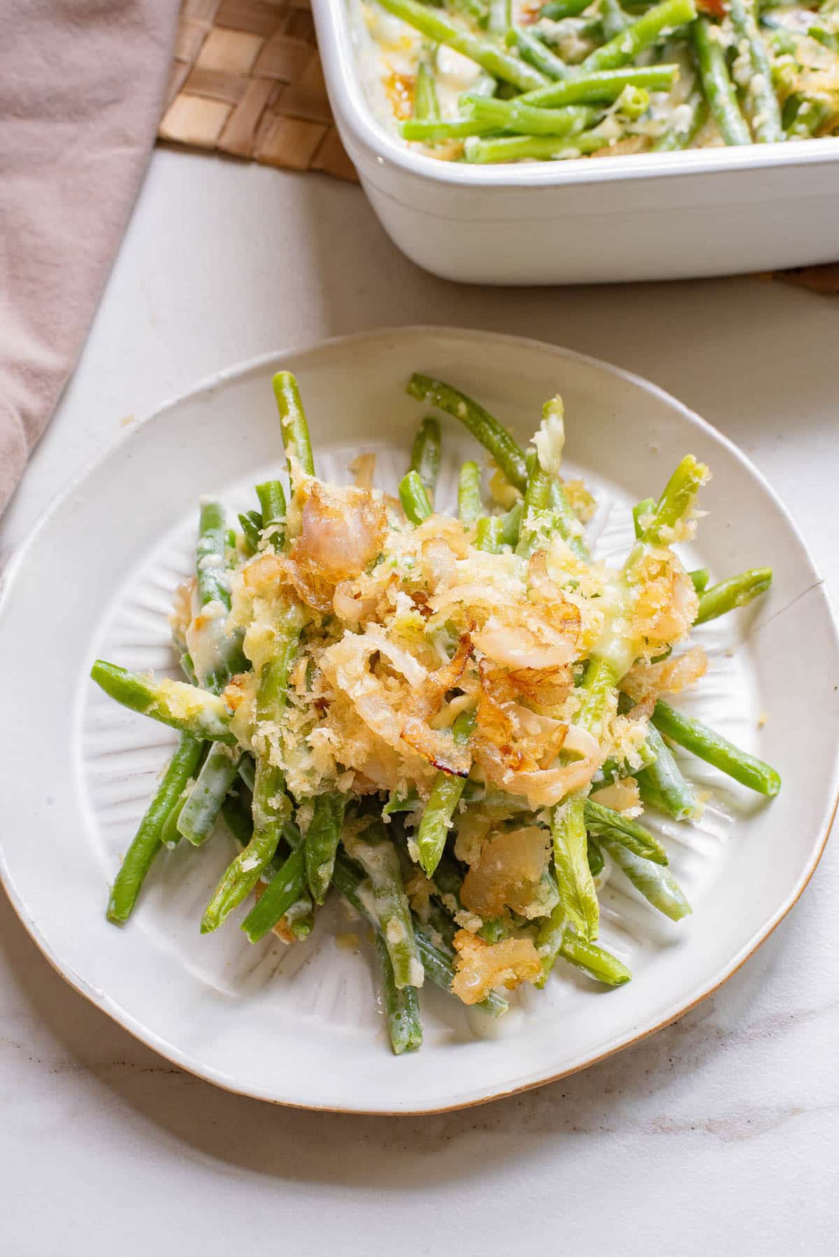 Green bean casserole with crispy onions on a white plate.