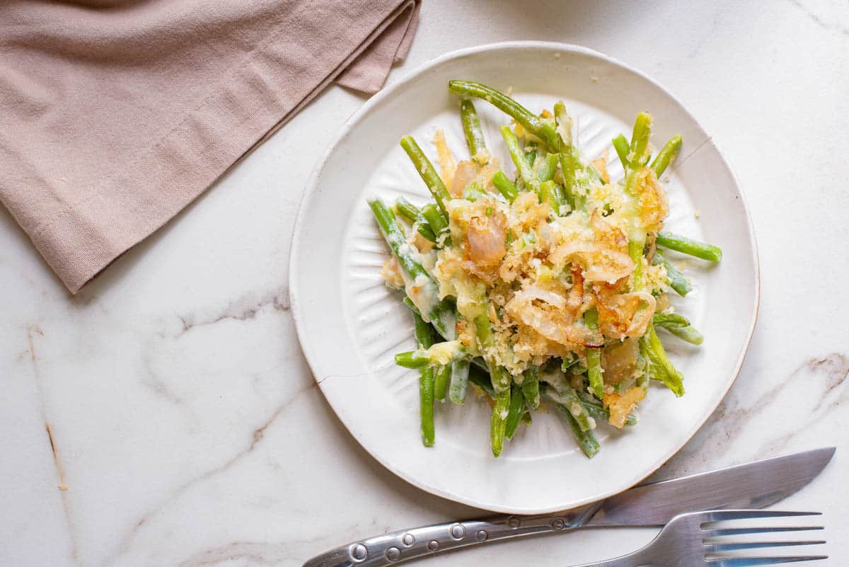 Green bean casserole with crispy onions on a white plate.