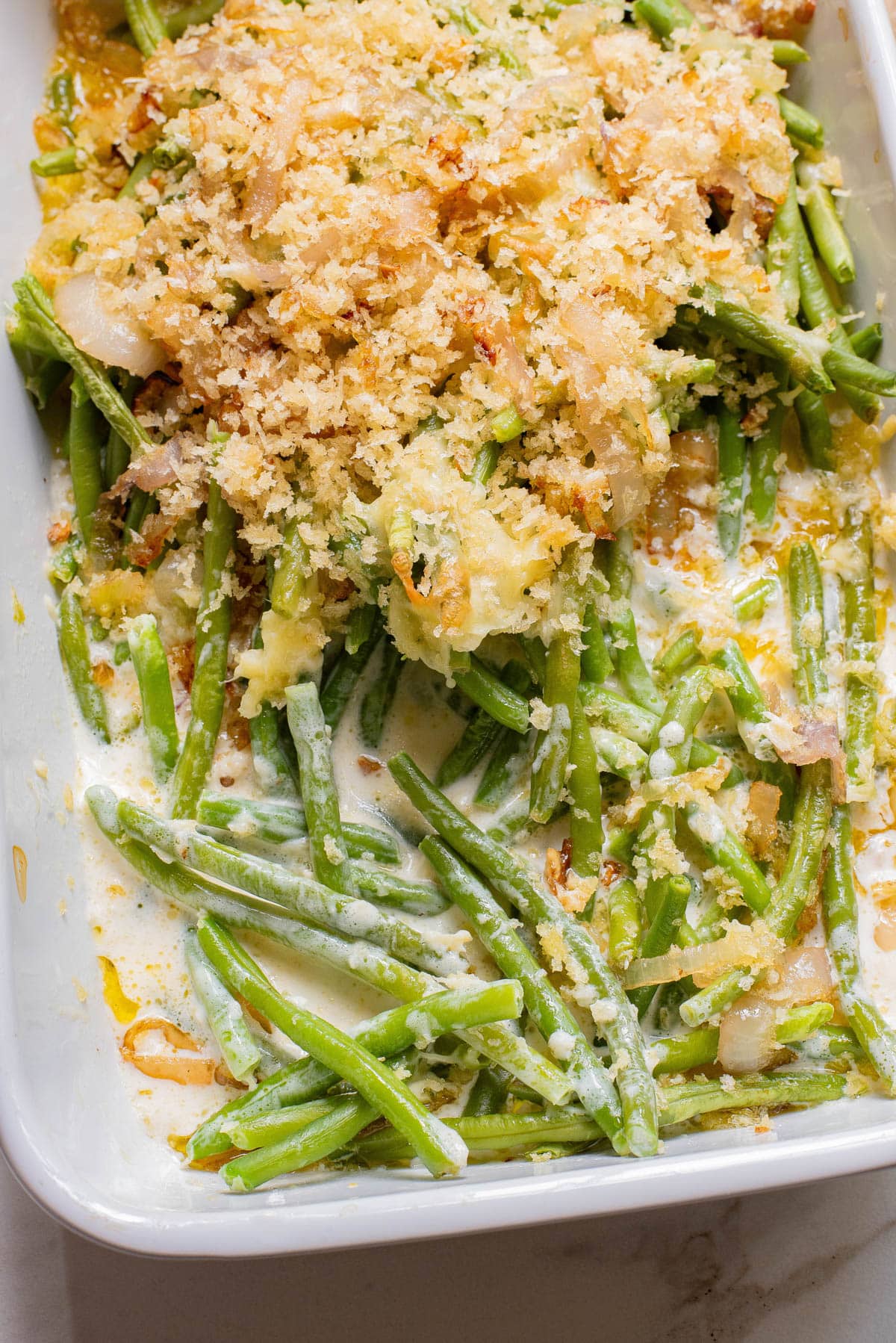 Green beans in white baking dish with crispy onion topping.