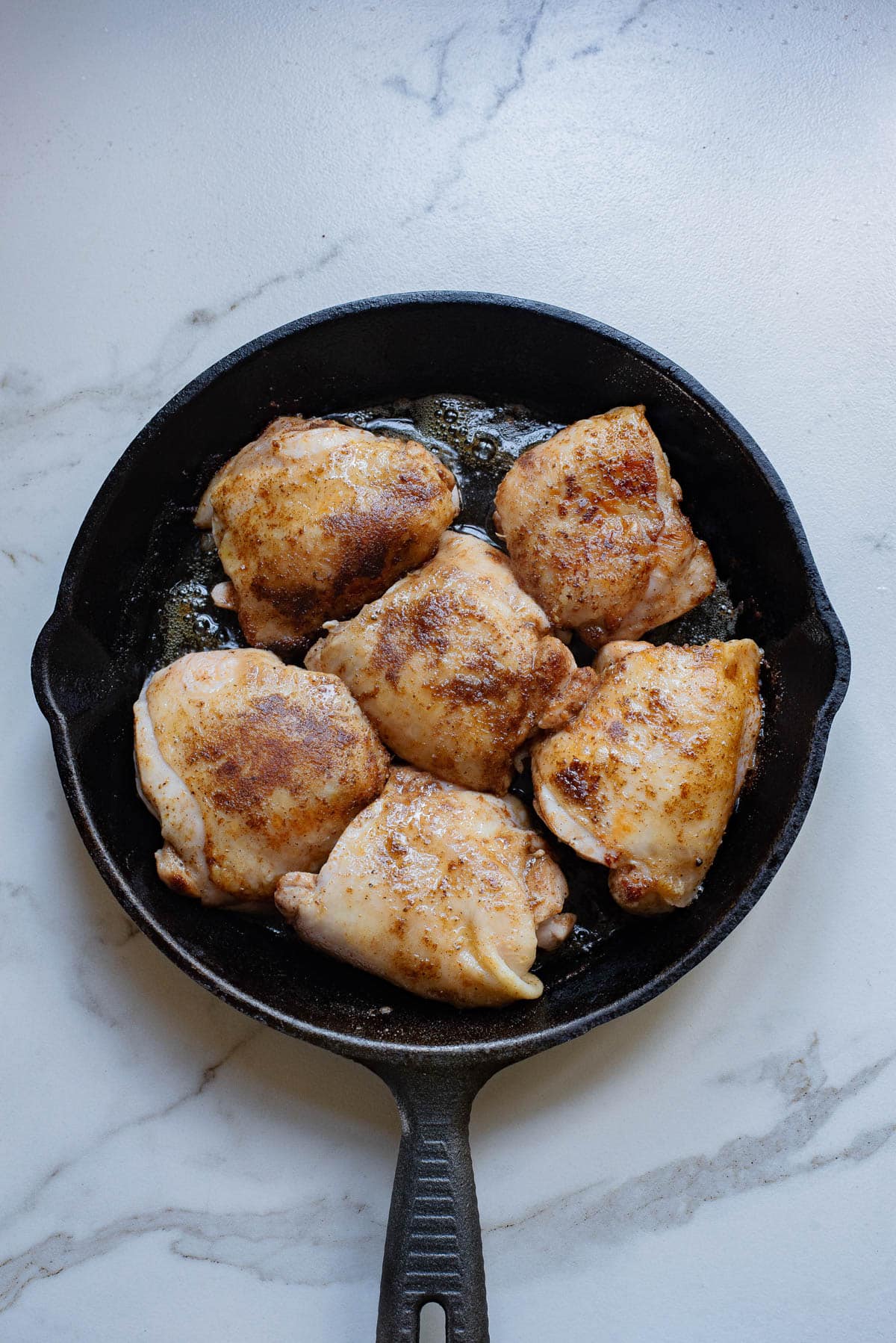 Seared chicken in cast iron pan.