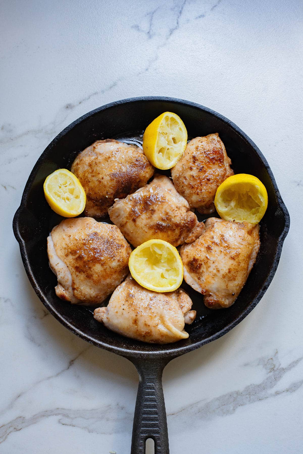Seared chicken with lemon in cast iron pan.