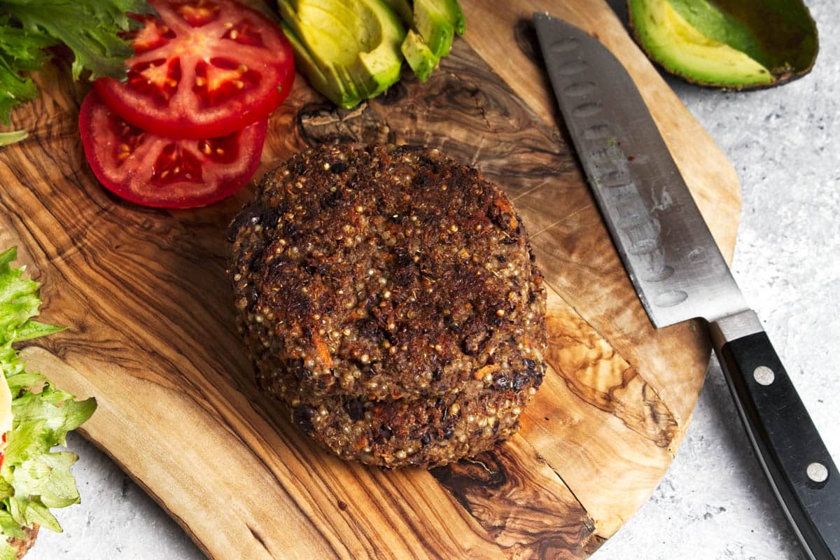 Black bean burger with lettuce, tomato, and avocado on a sesame seed bun.
