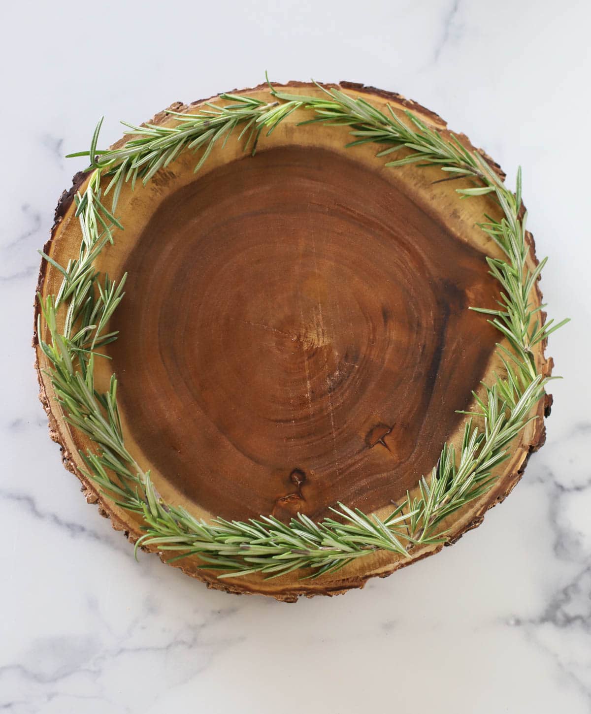 Round board rimmed with rosemary.
