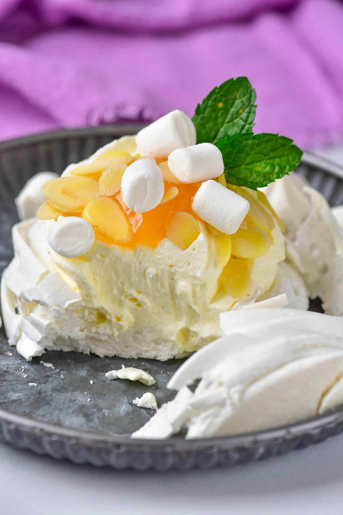 Pavlova dessert with almonds, lemon curd, marshmallow, and mint.