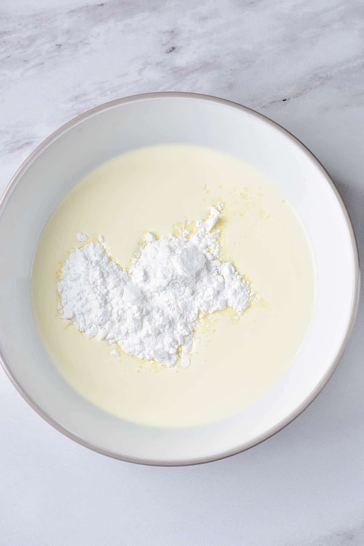 Heavy cream and powdered sugar in a white bowl.