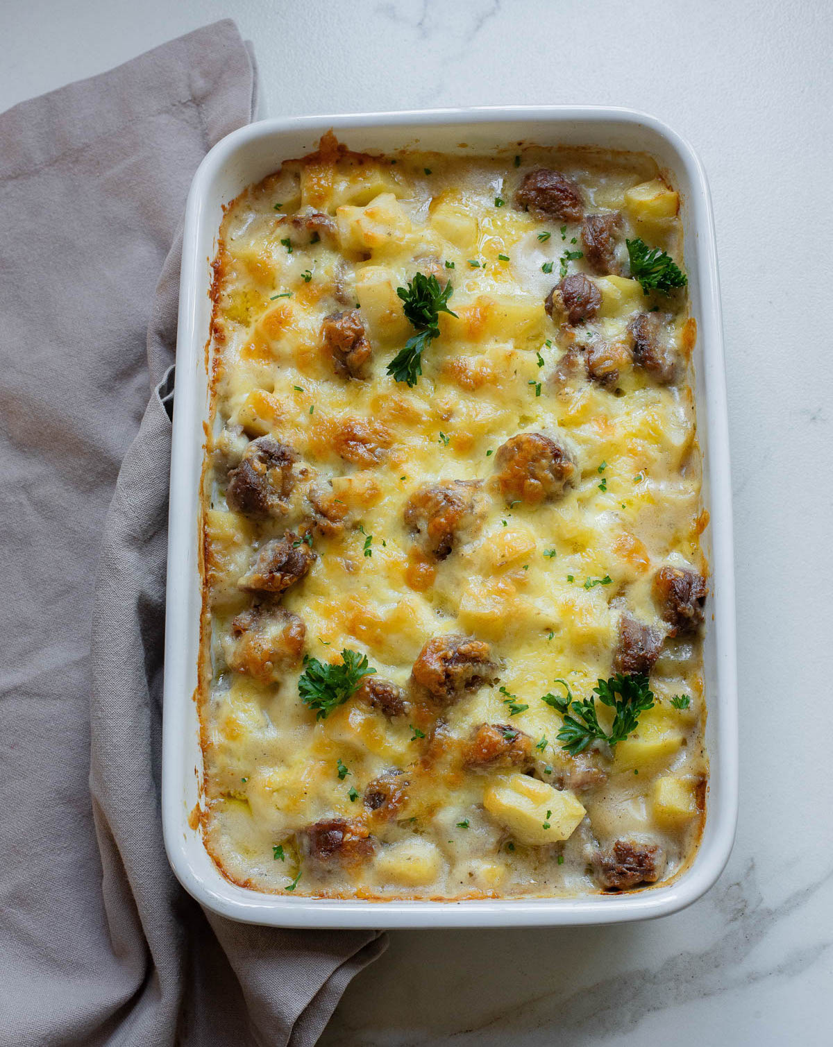 Cheese potato and smoked sausage casserole in a white dish.