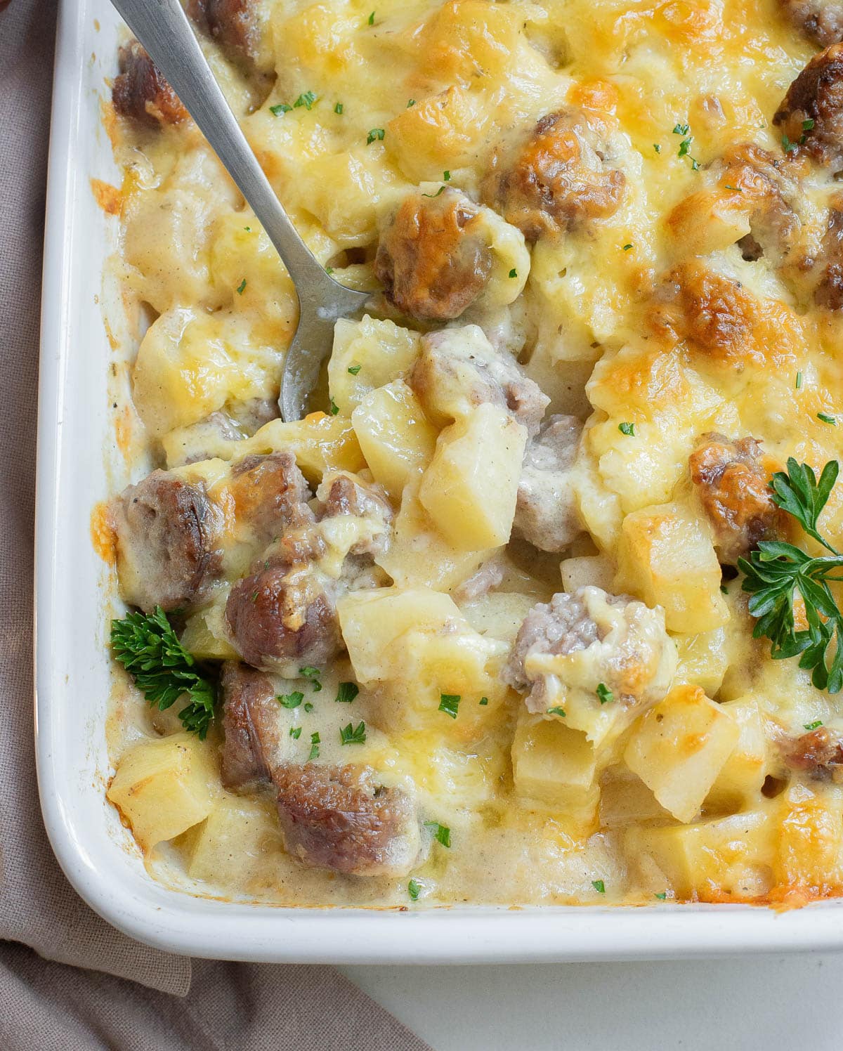 Cheesy Potato and Smoked Sausage in a white casserole dish.