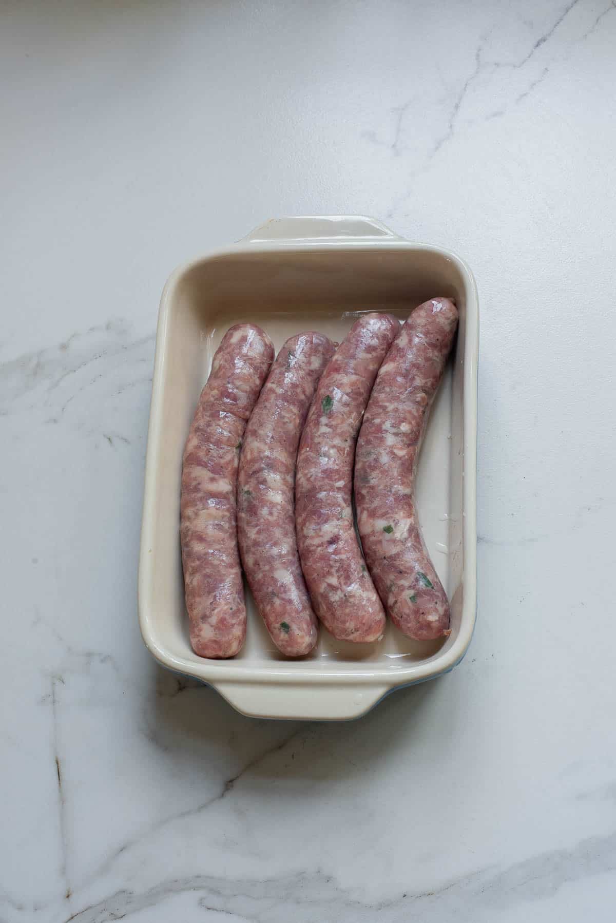 Raw sausage in a casserole dish.