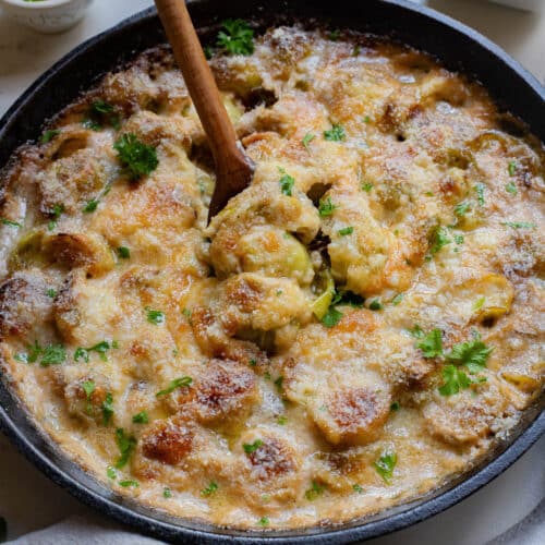 Brussels sprouts in a cast iron pan with golden brown cheese topping.