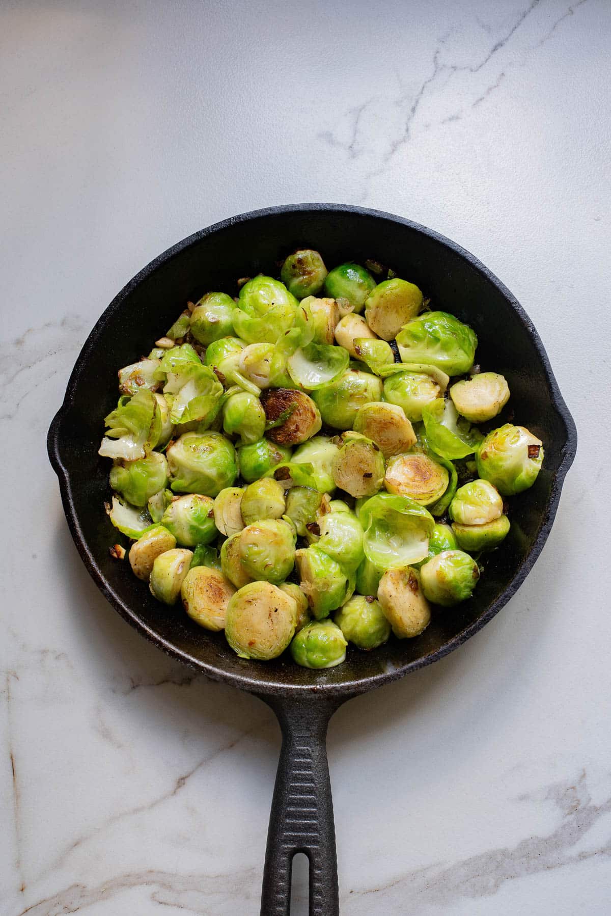 Brussels sprouts in a cast iron pan with onions and garlic.