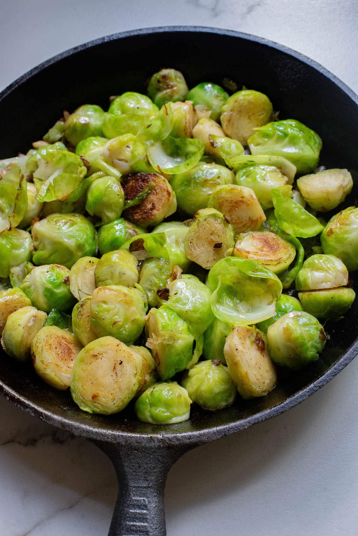 Brussels sprouts in a cast iron pan with onions and garlic.