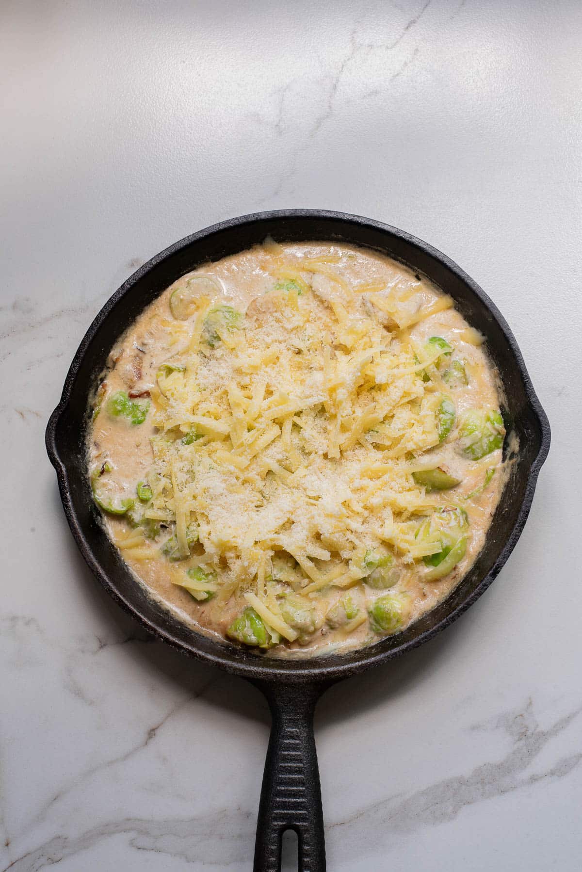 Brussels sprouts in a cast iron pan with cream, cheese, onions and garlic.