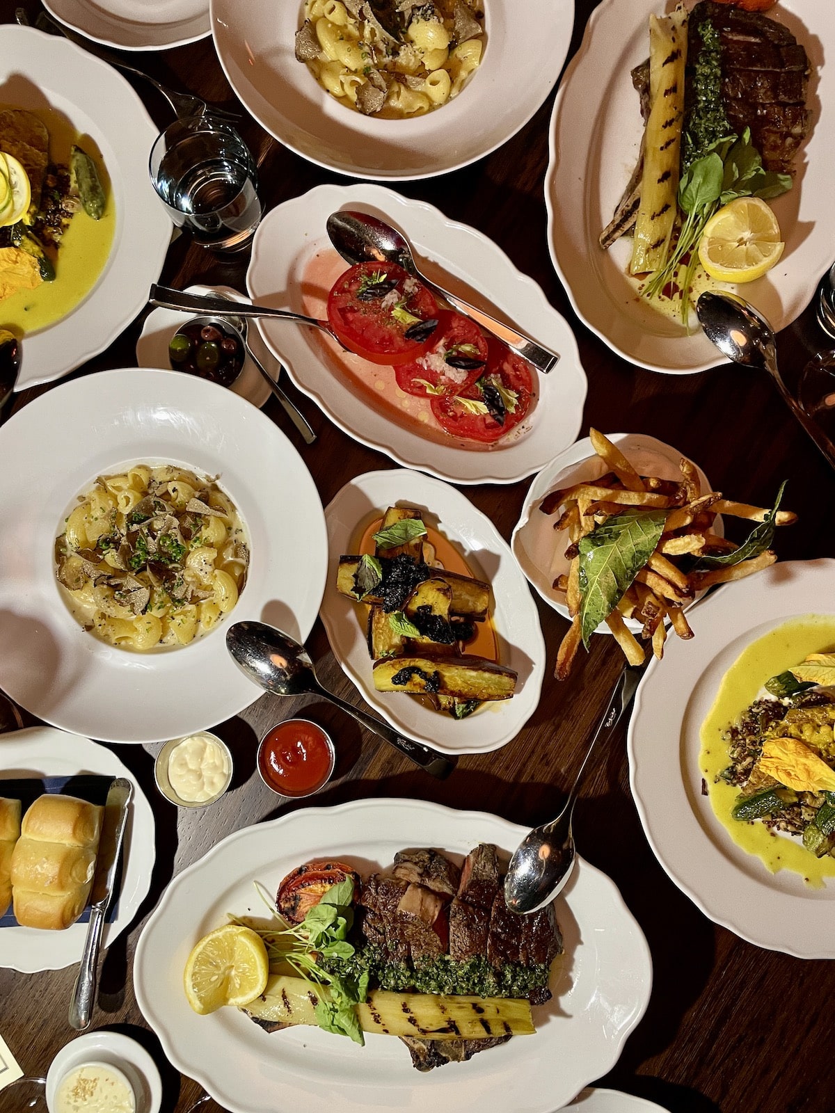 Many different foods on white dishes in wood table.