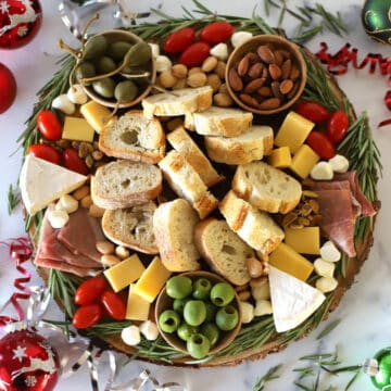 Round wood board with charcuterie decorated for Christmas.