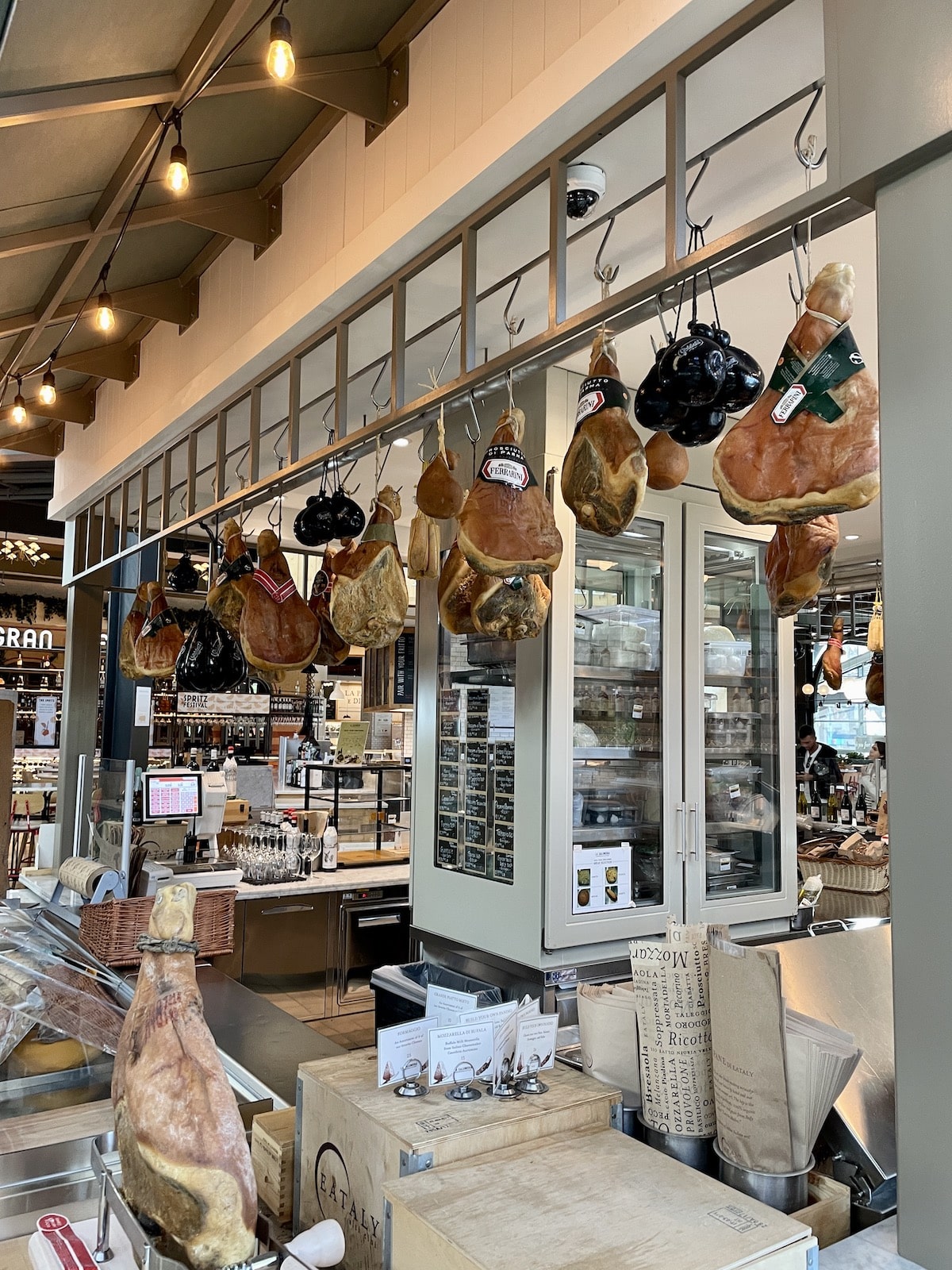 Italian meat counter with meats hanging from above.
