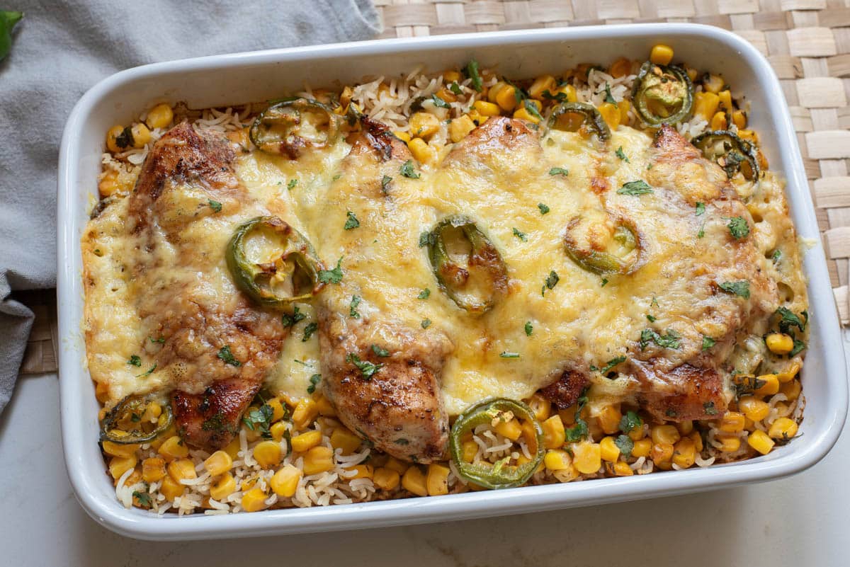 Chicken and rice with jalapenos and cheese in a white baking dish.