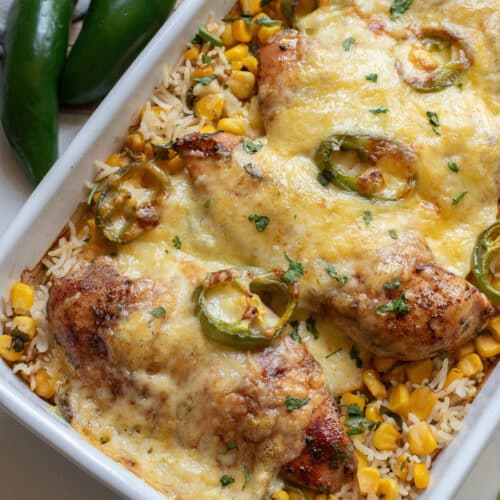 Chicken and rice with jalapenos and cheese in a white baking dish.