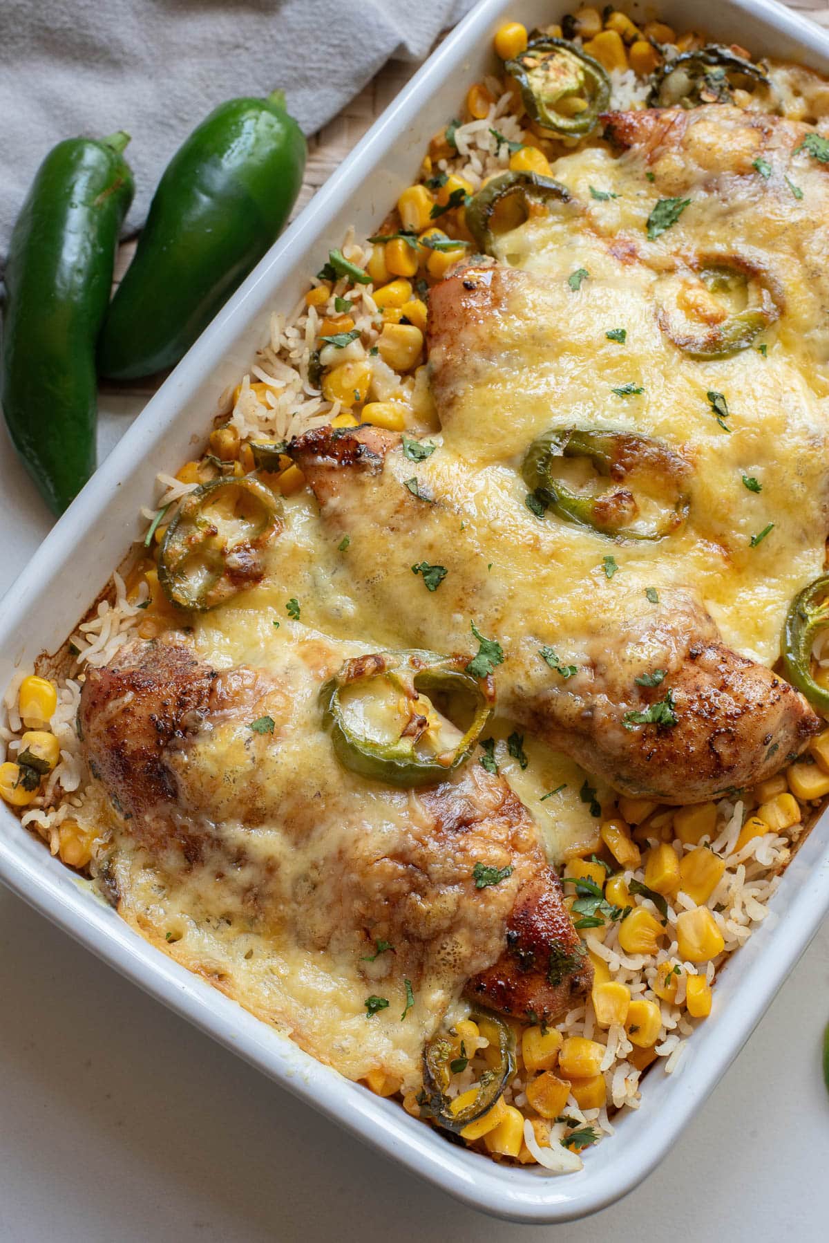 Chicken and rice casserole covered with cheese in a white baking dish.