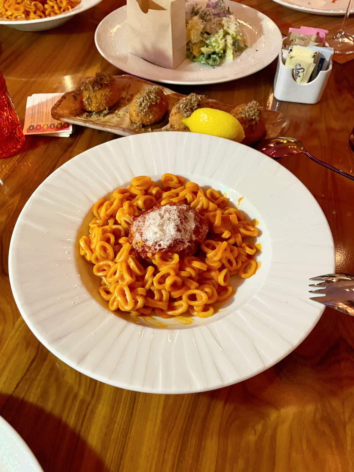 Retro round pasta on a white plate with shredded cheese.