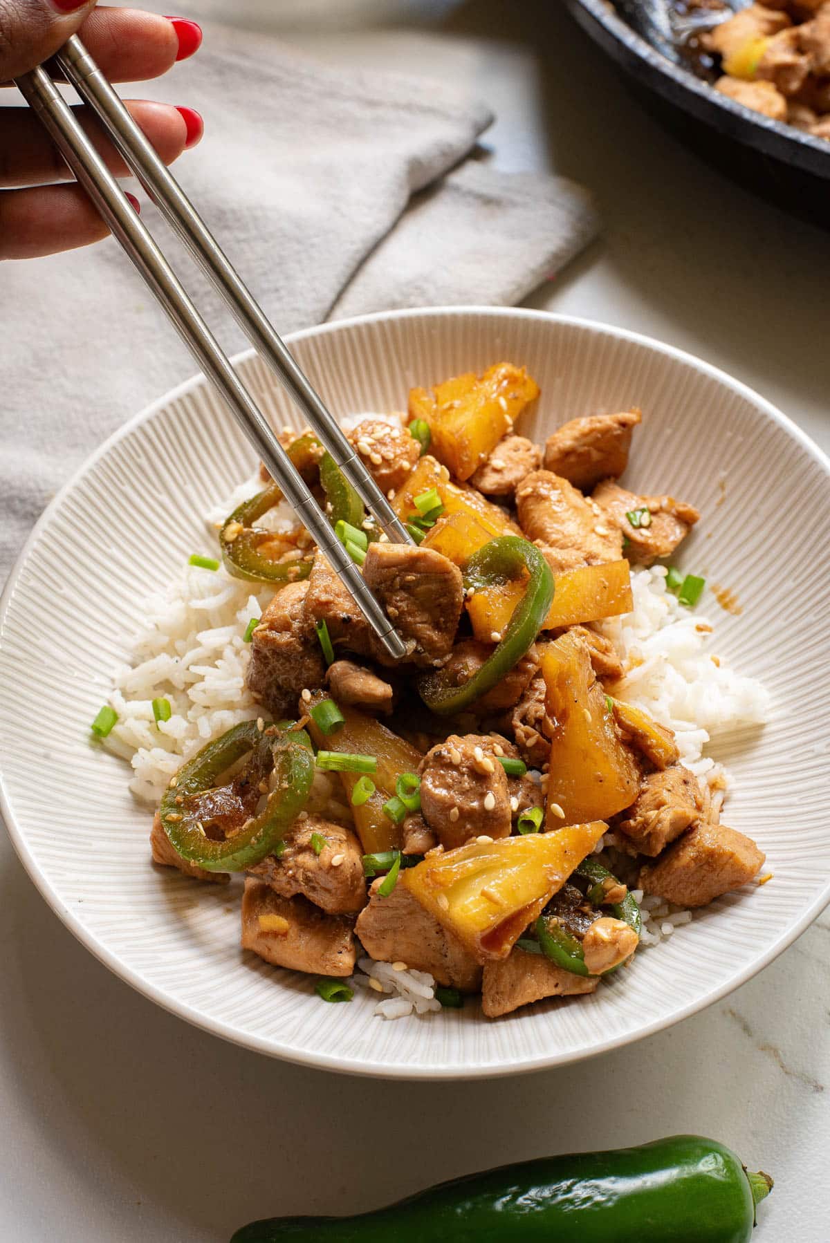 Chicken, pineapple, and jalapenos over white rice in white bowl.