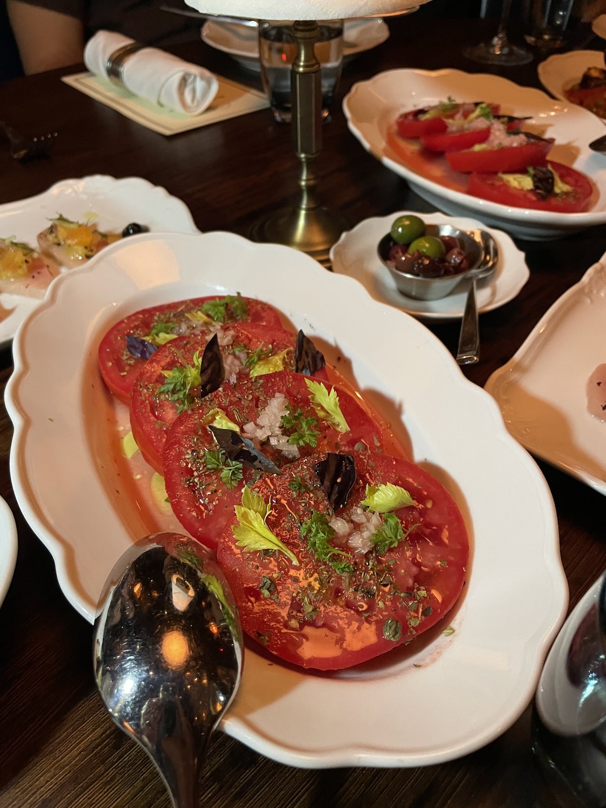 Tomatoes with seasoning and oil on a white plate.