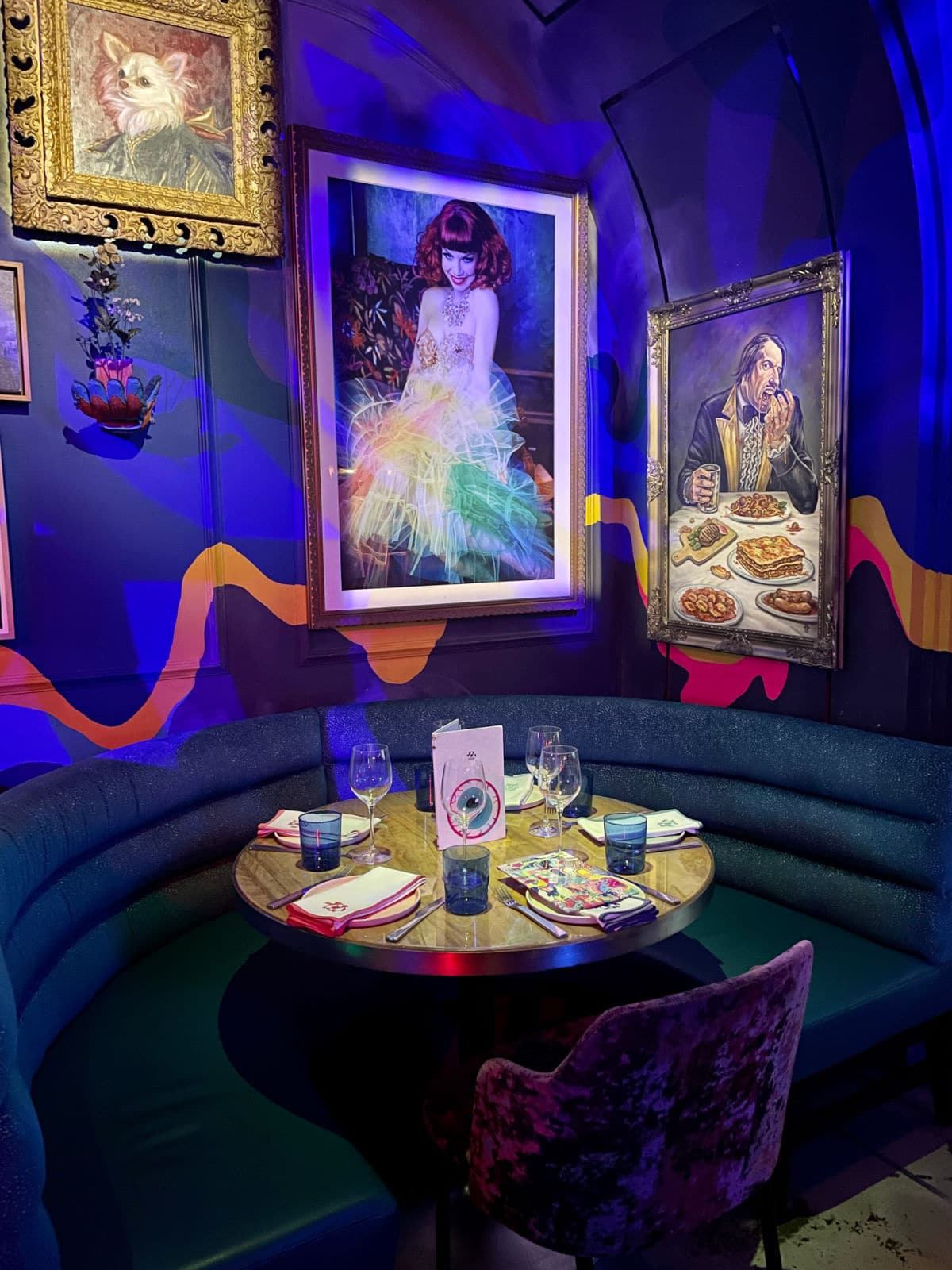 Table set for four with paintings and black lights in background.