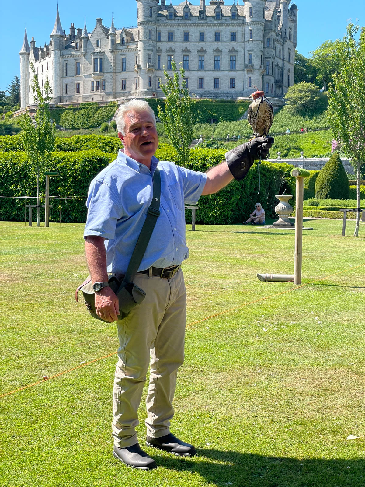 Man holding a falcon in front of a castle.