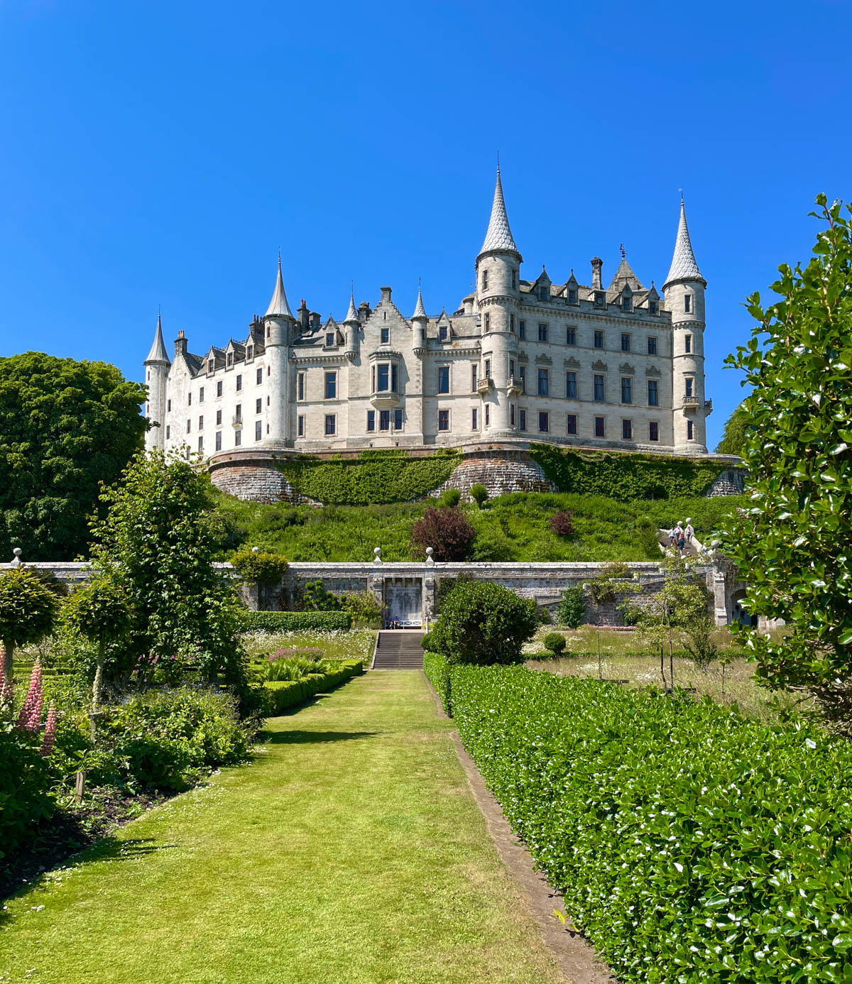 Castle on a hill with gardens in the forefront.