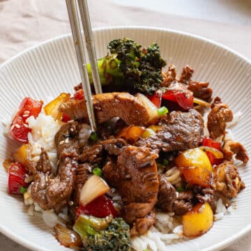 Chicken and steak with vegetables in a stir fry sauce over rice.
