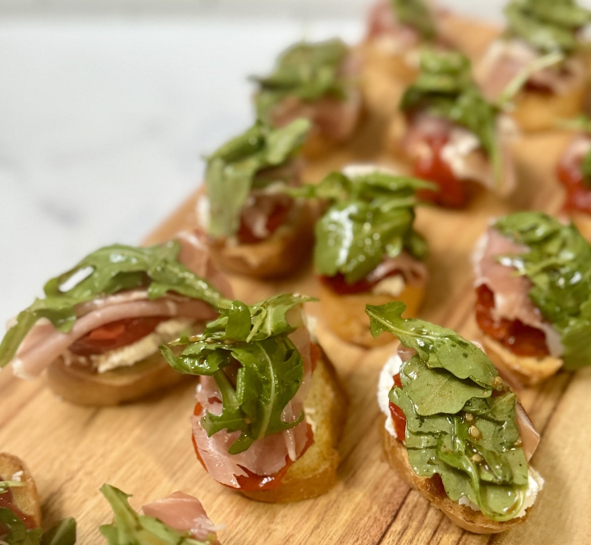 Goat cheese and prosciutto with tomato on toasts.