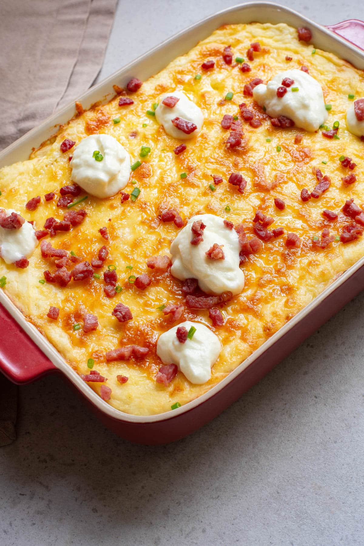 Potato casserole with bacon, cheese, and sour cream on top.