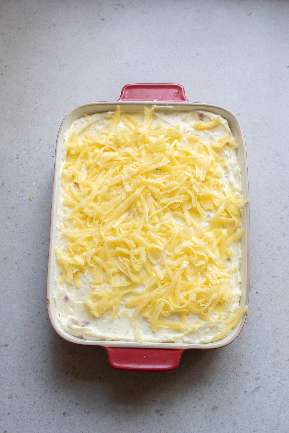 Mashed potatoes and cheese in a baking dish, uncooked.