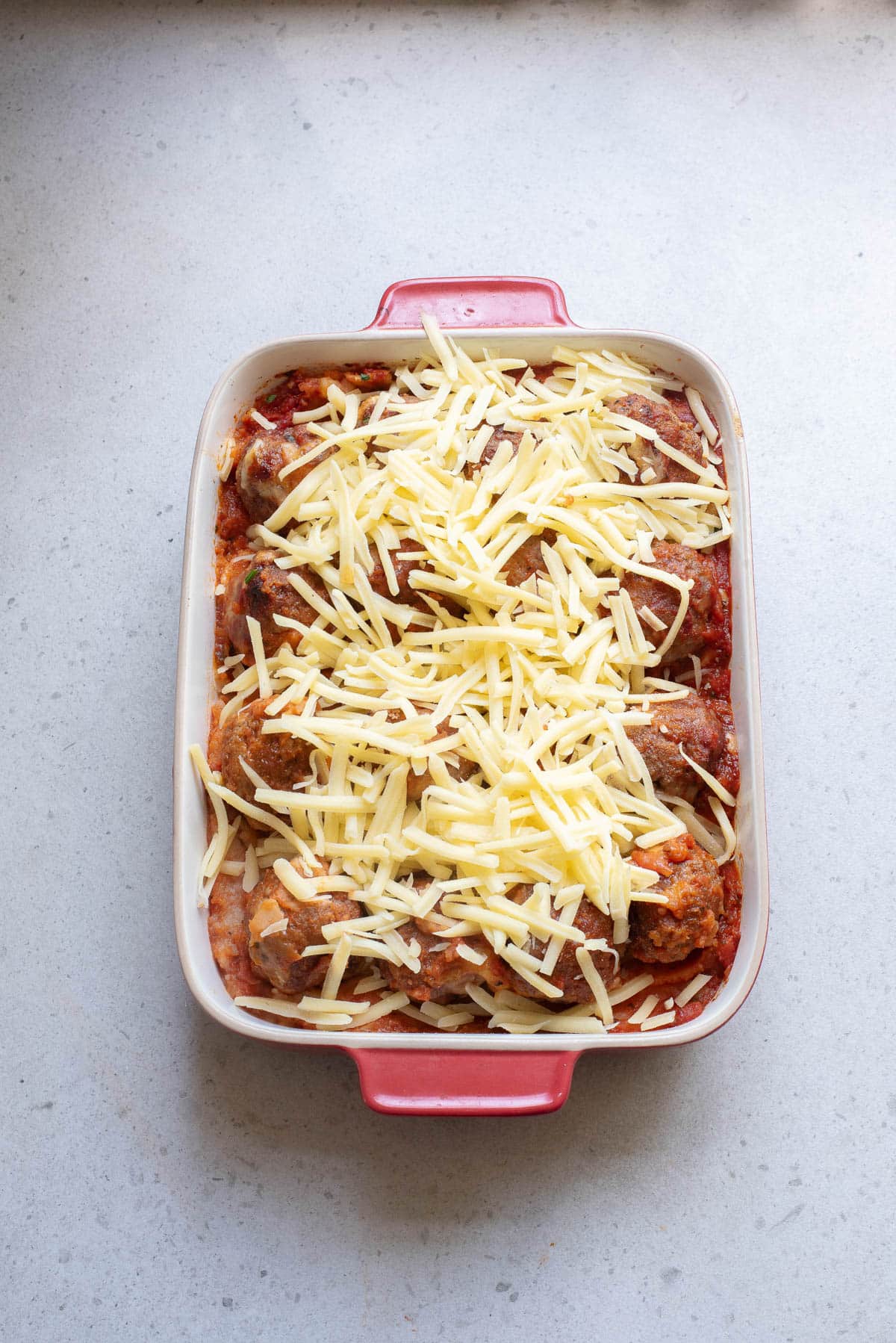 Meatballs in marinara and cheese baked in a casserole dish topped with cheese.