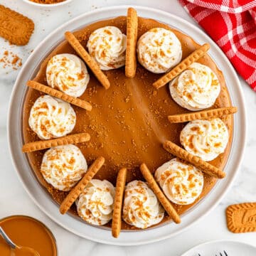 Biscoff cheesecake decorated with whipped cream and cookies.