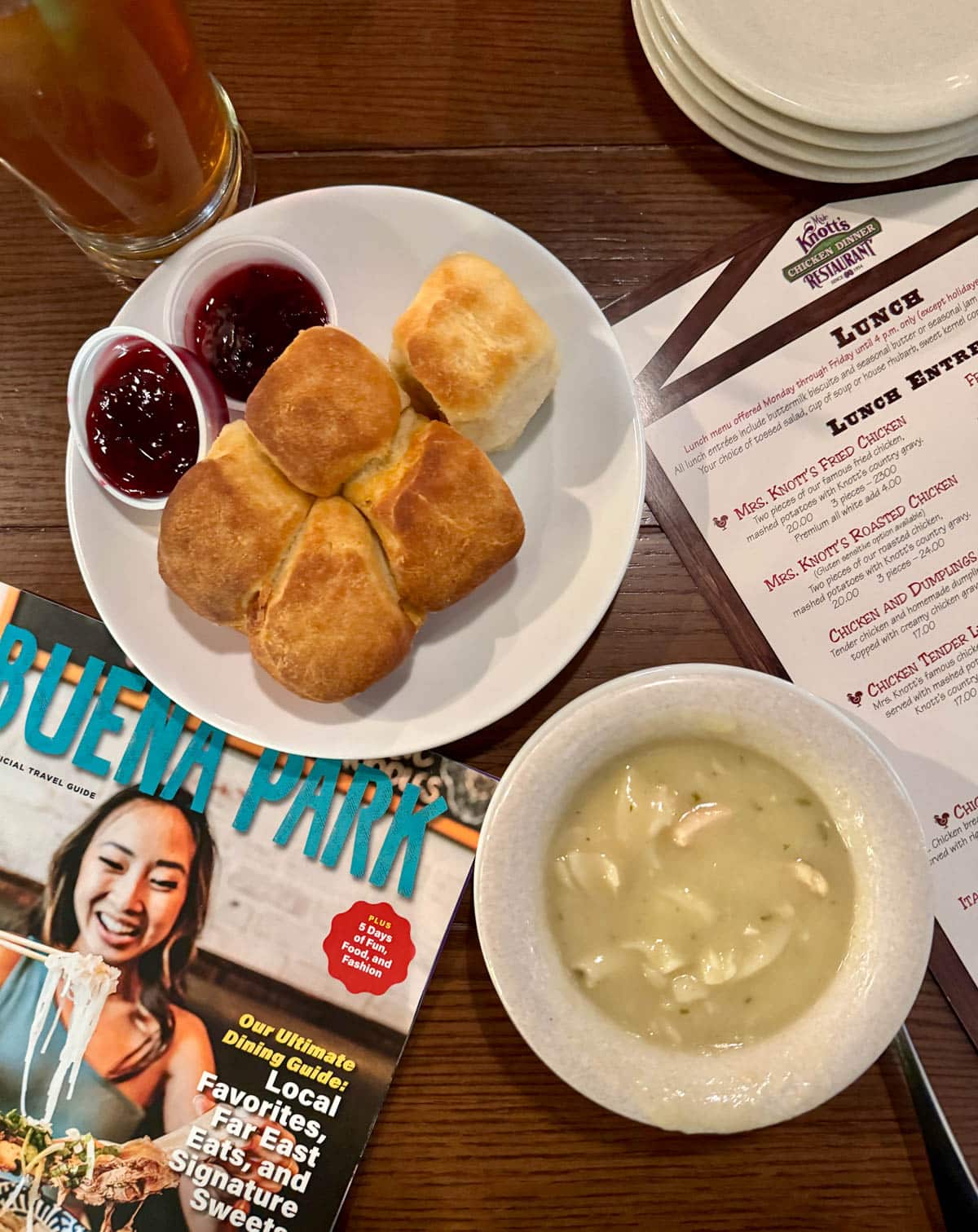 Chicken soup and biscuits with menu and Buena Park magazine on wood table.