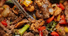 Chicken and steak stir fry with vegetables and sauce with text for Pinterest.