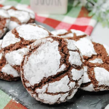 Chocolate crinkle cookies on a Christmas plaid tablecloth.