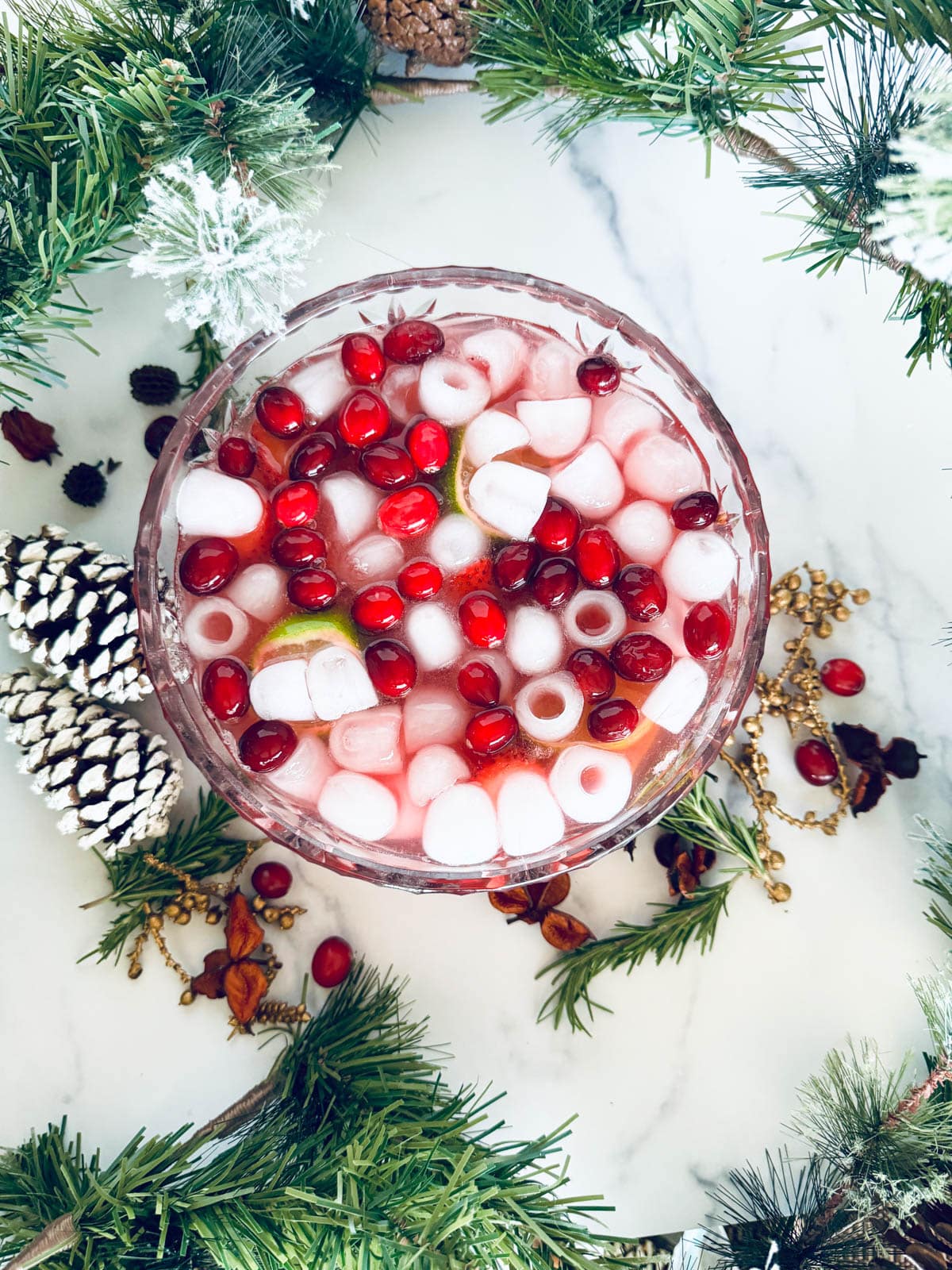 Cranberry and champagne punch with fruit in a glass bowl with Christmas decor.
