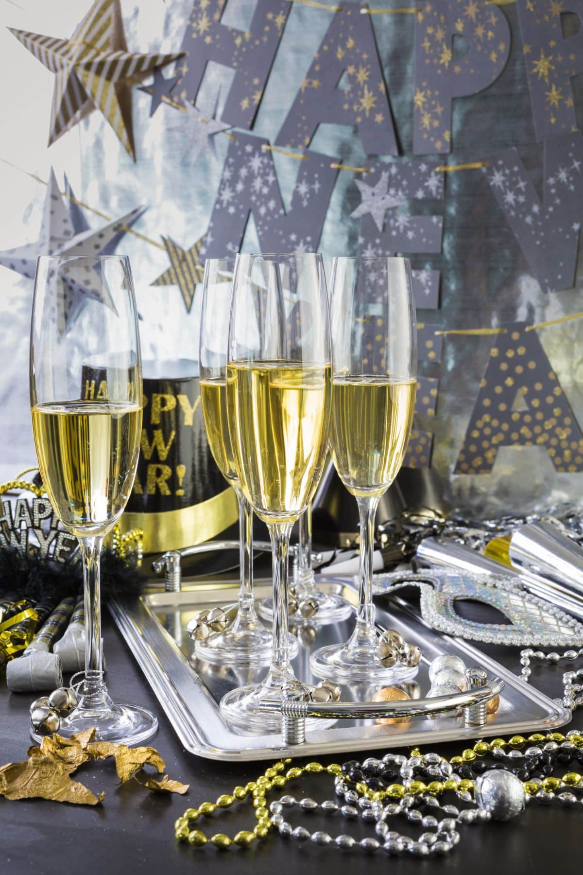 New Year's party with glasses of champagne on a silver tray and gold and silver beads.