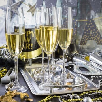 New Year's Eve celebration with champagne and beads on a silver tray.
