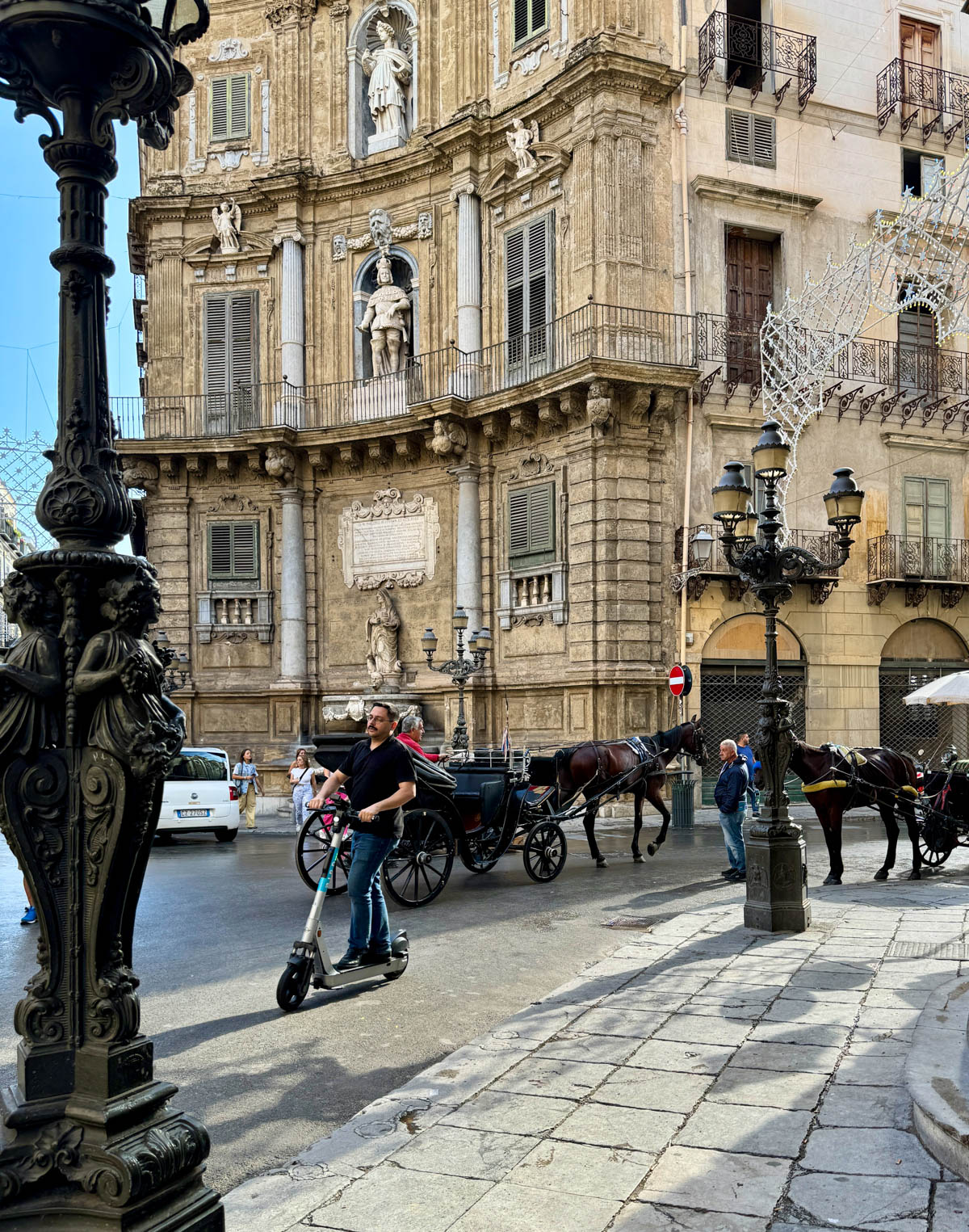 Horse and carriage in front of building with many on segway on road.