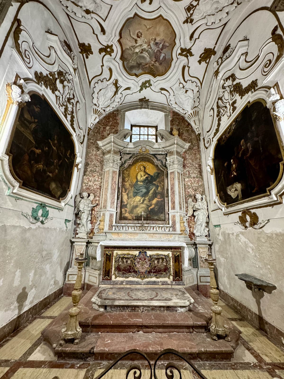 Inside of a church with marble alters and paintings.