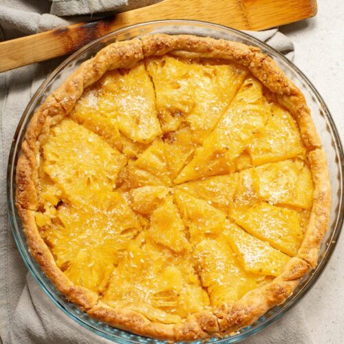 Pineapple pie with napkin and wooden spoon on counter.