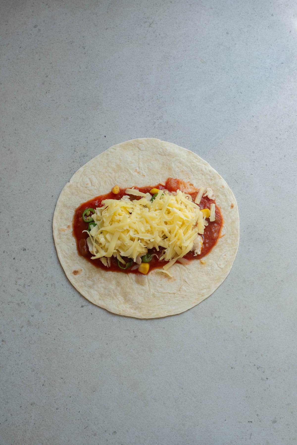 Tortilla with filling and cheese on top.