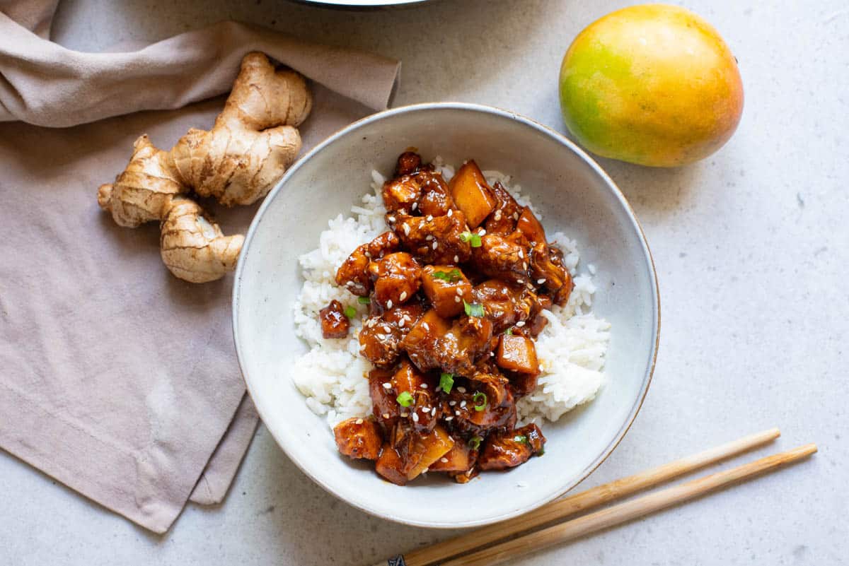 Chinese bourbon chicken in a white bowl over rice.